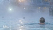Menschen schwimmen in einem Freibad, Dampf steigt aus dem Wasser auf © Screenshot 