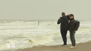 Menschen stehen bei Sturm an einer Meeresküste © Screenshot 