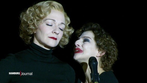 Zwei Schauspielerinnen, die Marlene Dietrisch und Edith Piaf verkörpern, nähern sich in einer Szene auf der Bühne an. © Screenshot 