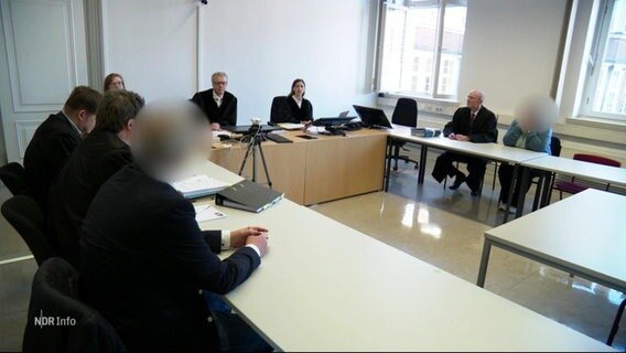 In einem Verhandlungssaal sitzen Kläger und Angeklagte sowie die Richter beieinander. © Screenshot 