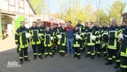 Menschen der Feuerwehr auf einer Straße versammelt © Screenshot 