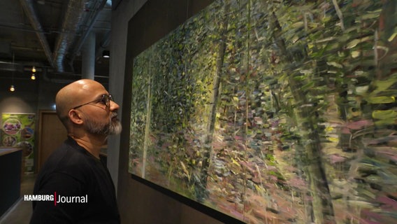 Arup J. Paul betrachtet ein Gemälde an der Wand. © Screenshot 