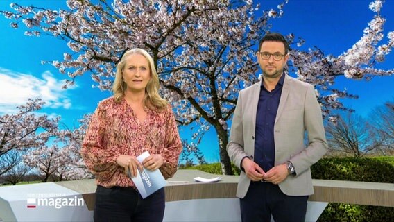 Das Moderatorenteam Harriet Heise und Christopher Scheffelmeier, im Hintergrund ein Bild eines blühenden Baumes. © Screenshot 