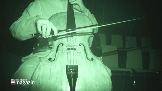 Ein Musiker spielt auf einem Cello. Der Person ist grünlich ausgeleuchtet, da sie mit einer Infrarotkamera aufgenommen wurde. © Screenshot 