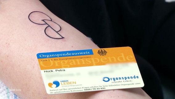 Ein Organspendeausweis liegt auf einem Arm, daneben ein frisch gestochenes Tattoo © Screenshot 