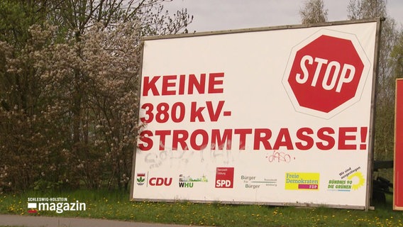 An einer Straße steht ein großes Schild mit der Aufschrift: "Keine 380kV-Stromstrasse!" © Screenshot 