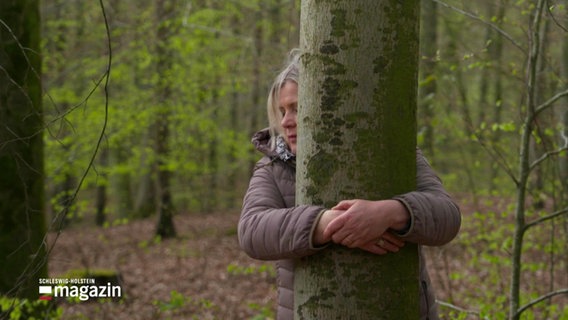 Eine Frau umarmt einen Baum © Screenshot 