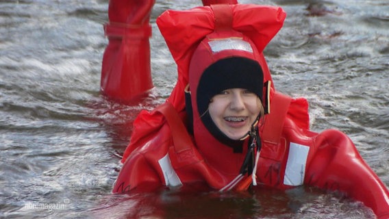 Eine Schülerin in einem Rettungsanzug im Wasser. © Screenshot 