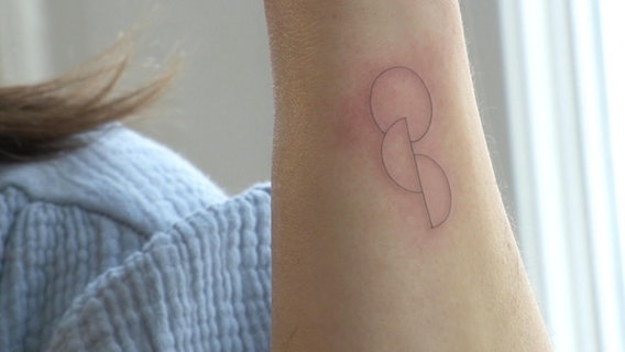 Eine Person präsentiert ihr frisch gestochenes ein Tattoo am Arm. © Screenshot 