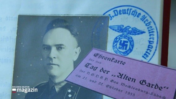 Eine alte Fotografie zeigt Gestapo-Chef Ludwig Oldach aus Schwerin, dahinter ein Stempel mit Reichsadler und Hakenkreuz. © Screenshot 