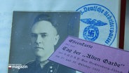 Eine alte Fotografie zeigt Gestapo-Chef Ludwig Oldach aus Schwerin, dahinter ein Stempel mit Reichsadler und Hakenkreuz. © Screenshot 
