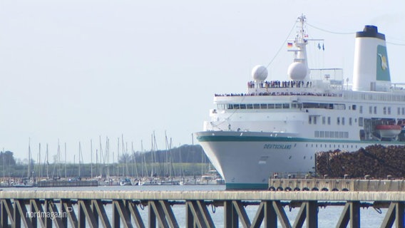 Ein größeres Kreuzfahrtschiff fährt in einen Hafen ein. © Screenshot 