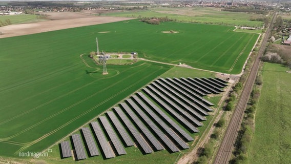 Auf einem größeren, grünen Feld ist ein Teil von einem Solarpark bebaut. © Screenshot 