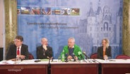 Vier Personen bei einer Pressekonferenz. © Screenshot 