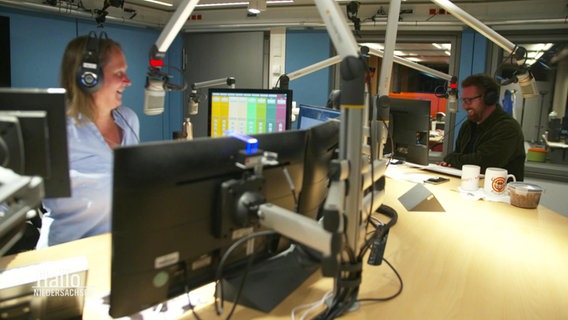 Die Radiomoderierenden Susanne Neuß und Andreas Kuhlage stehen bei einer Sendung zusammen im Studio. © Screenshot 