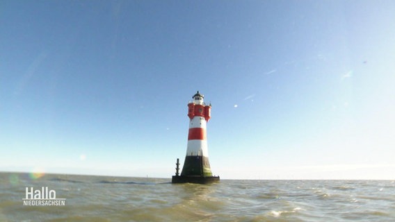 Vlick auf einen mitten im Meer stehenden, rot-weißen Leuchtturm. © Screenshot 
