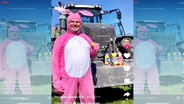 TikTok-Ausschnitt: Ein Mann in einem rosa Osterhasenkostüm hält vor einem Traktor ein Osterei hoch. © Screenshot 