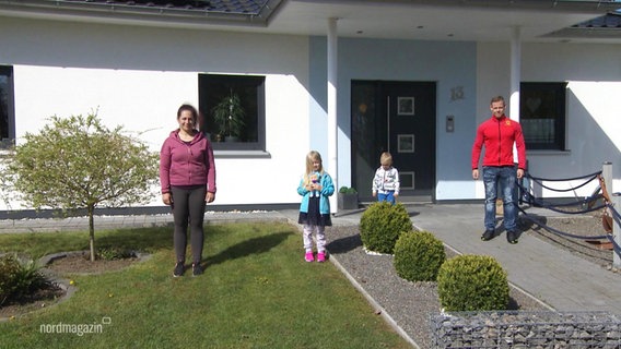A family with two children is standing in the front yard of their newly built house.  ©screenshot 