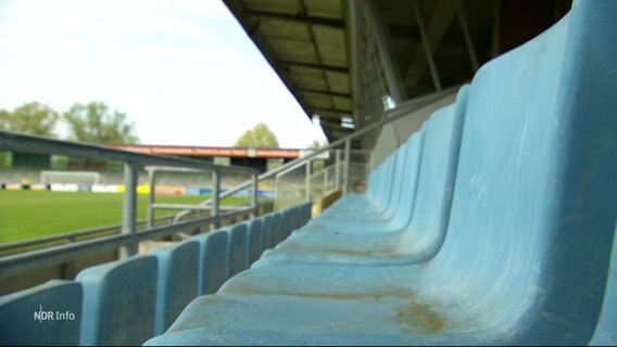 Leere Plastiksitze einer Tribüne auf dem Fußballfeld eines kleineren Regionalvereins. © Screenshot 