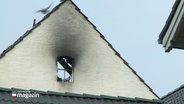 An der Fassade eines Wohnhauses sind schwarze Rauchflecken unter der Dachgiebelung über einem Fenster nach einem Brand im Dachstuhl zurückgeblieben. © Screenshot 