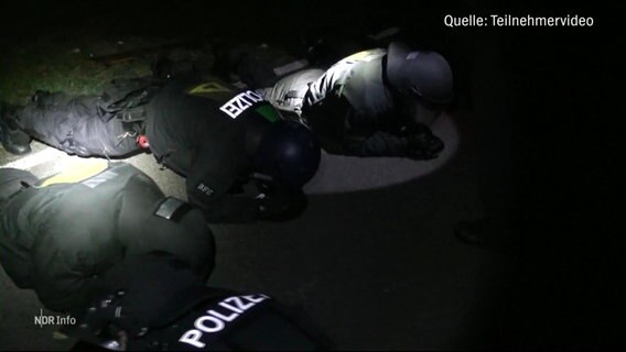 Bei einer nächtlichen Polizeiübung machen Einsatzkräfte der Polizei in voller Demo-Montur Liegestütze im Taschenlampenlicht. © Screenshot 