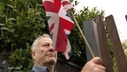 Philip Ward bringt eine britische Flagge an seinem Gartenzaun an. © Screenshot 