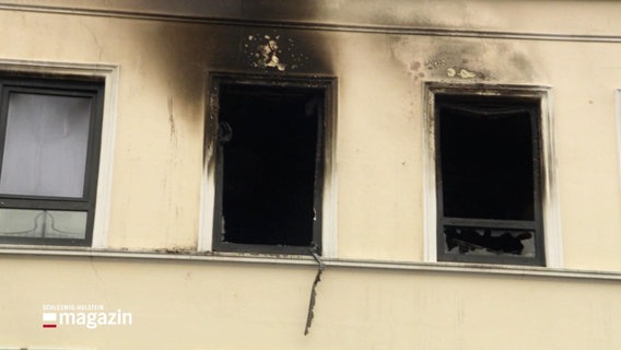 Über zwei Fenstern eines Wohnhauses sind starke Rußrückstände des Brandes zu erkennen. © Screenshot 
