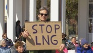 Ein Demonstrant hält ein Schild mit der Aufschrift "Stop LNG". © Screenshot 