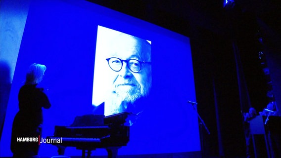 In Gedenken an Jürgen Flimm wird ein Portrait auf die Theaterbühne projeziert. © Screenshot 