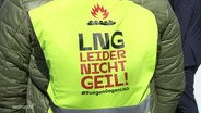 Die Rückseite einer gelben Warnweste trägt die Aufschrift: "LNG - Leider Nicht Geil". © Screenshot 