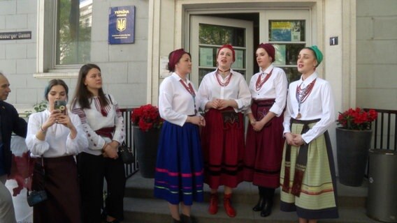 Eine singende Gruppe von Frauen in traditionellen Trachten aus der Ukraine vor dem ukrainischen Konsulat. © Screenshot 