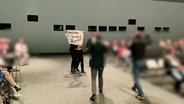 Aktivist:innen stürmen die Bühne bei einer Versammlung von VW-Aktionären. © Screenshot 