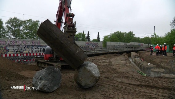 Ein Bagger bewegt Steine auf einer Baustelle. © Screenshot 