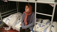 Eine nach Deutschland geflüchtete Frau sitzt auf ihrem Bett in der Unterkunft. © Screenshot 