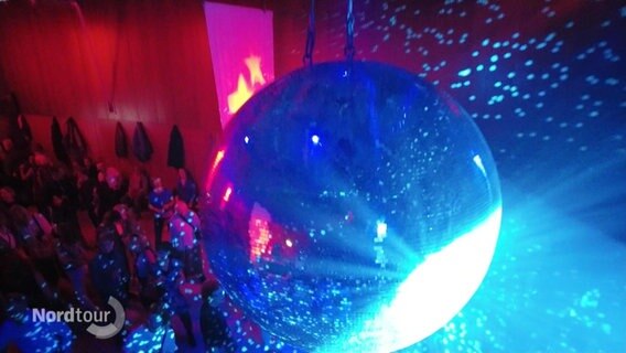 Eine Discokugel wird mit buntem Licht beleuchtet. © Screenshot 