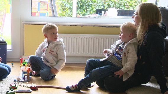 Mats und Luca sitzen mit ihrer Mutter im Wohnzimmer. © Screenshot 