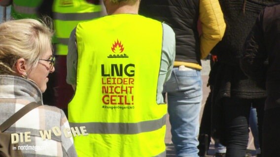 Eine Person trägt eine gelbe Warnweste mit der Aufschrift: "LNG - Leider NIcht Geil!" © Screenshot 