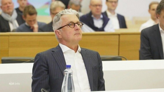 Der Ex-Audi Manager Rupert Stadler sitzt bei einem Gerichtstermin im Nadelstreifenanzug auf der Anklagebank. © Screenshot 