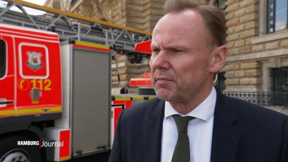 Der Hamburger Innensenator Andy Grote (SPD) steht vor einem Feuerwehrauto vor dem Hamburger Rathaus und gibt ein Interview. © Screenshot 