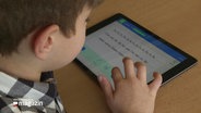 Ein kleinerer Junge bedient ein Tablet mit einer Lesenlern-App. © Screenshot 