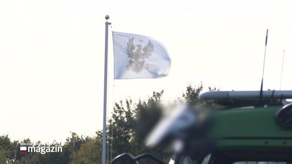 Das Preußische Wappen, der Reichsadler auf weißem Grund, auf einer wehenden Flagge - das Symbol der Reichsbürger. © Screenshot 