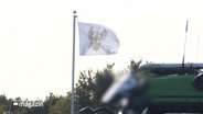 Das Preußische Wappen, der Reichsadler auf weißem Grund, auf einer wehenden Flagge - das Symbol der Reichsbürger. © Screenshot 