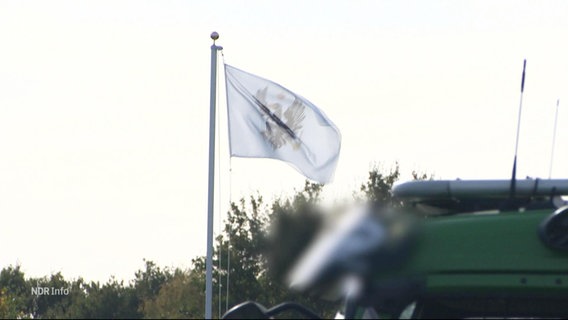 An einem kleineren Fahnenmast weht eine Reichsbürger-Flagge. © Screenshot 