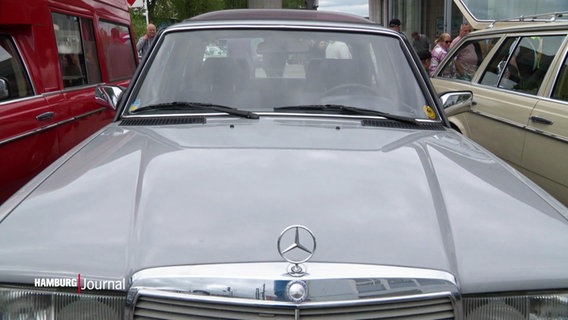 Blick ab der Motorhaube einer W123-Limousine von Mercedes auf die Frontscheibe und den ikonischen Mercedes-Stern. © Screenshot 