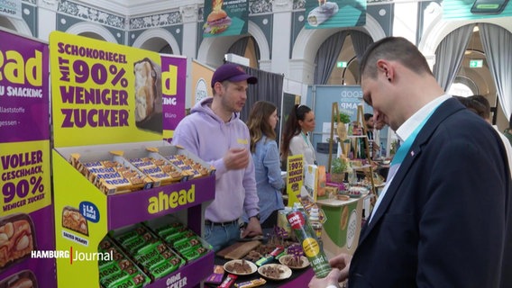 Ein Interessent lässt sich an einem Stand auf dem "Food Innovation Camp" in der Handelskammer Hamburg beraten. © Screenshot 