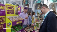 Ein Interessent lässt sich an einem Stand auf dem "Food Innovation Camp" in der Handelskammer Hamburg beraten. © Screenshot 