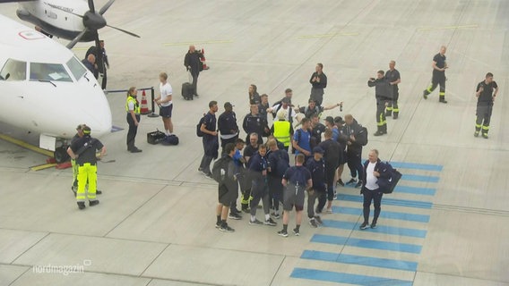 Spieler von Hansa Rostock stehen auf dem Rollfeld des Rostocker Flughafens. © Screenshot 