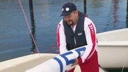 Alexander Knaub verpackt ein Segel auf einem kleinen Sportsegelboot. © Screenshot 