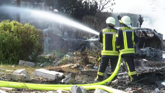 Zwei Feuerwehrleute bei Löscharbeiten an einem brennenden Haus. © Screenshot 
