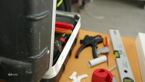 Werkzeuge liegen neben einem Koffer auf einem Tisch. © Screenshot 